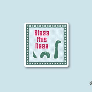 May include: A square sticker with a light blue background features a green Loch Ness Monster illustration. The text "Bless this Ness" is in red. The sticker has a white border with a green cross-stitch design.