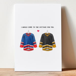 May include: A white card with the text "I would come to the cottage for you." features illustrations of two hockey jerseys and a pink heart. One jersey is blue with red and white accents, the other is black with gold and white accents.