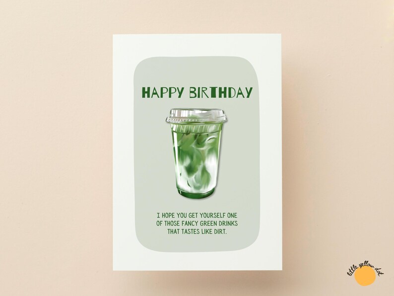 May include: A greeting card with the words "HAPPY BIRTHDAY" in green. The card features an illustration of a green drink in a clear plastic cup. The text below reads, "I HOPE YOU GET YOURSELF ONE OF THOSE FANCY GREEN DRINKS THAT TASTES LIKE DIRT."