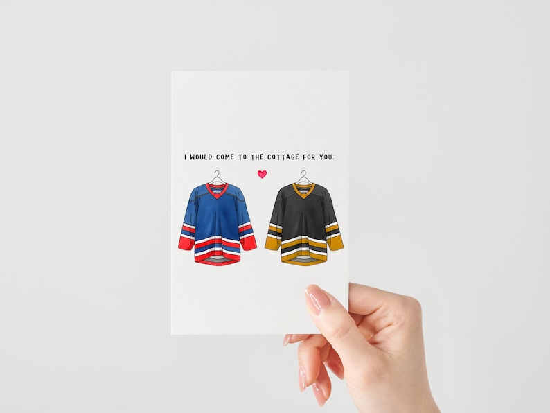 May include: A greeting card featuring illustrations of two hockey jerseys, one blue and red, the other black and gold, hanging on hangers. The text reads, "I would come to the cottage for you." A small pink heart is between the text and the jerseys.