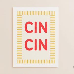 以下が含まれることがあります： 明るいクリーム色の背景に、中央に赤色の文字で「CIN CIN」と縦に並べられた長方形のプリント。デザインは、短い垂直線と水平線で構成された黄色の枠で囲まれています。下部には小さな黄色の円形ロゴがあります。
