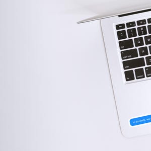 May include: A white laptop computer with a black keyboard and a blue message sticker that reads "in da clerb, we all fam".