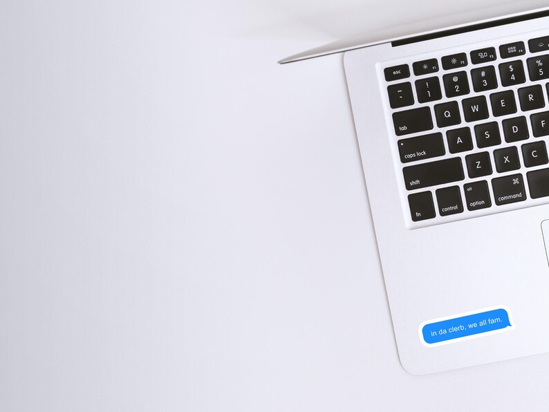 May include: A white laptop computer with a black keyboard and a blue message sticker that reads "in da clerb, we all fam".