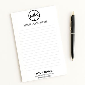May include: A white notepad with horizontal lines, a black pen, and a logo that says "MW" inside a circle. The notepad has the text "YOUR LOGO HERE", "YOUR NAME", your email, and a phone number.