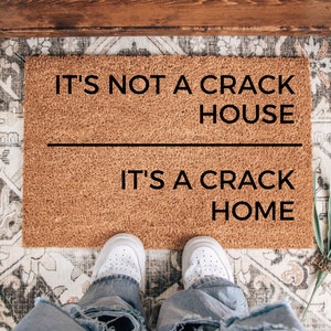 May include: A brown doormat with the text "It's not a crack house, it's a crack home" printed in black.