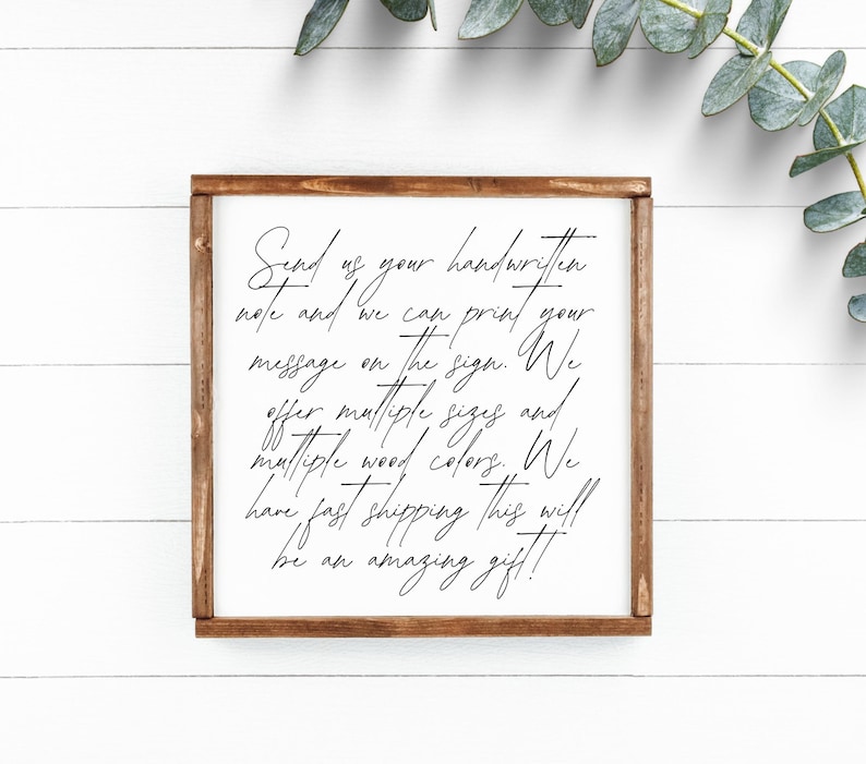 Brown framed custom handwriting sample sign on white boards beside eucalyptus.