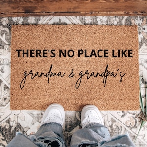 May include: A brown coir doormat with the text "THERE'S NO PLACE LIKE grandma & grandpa's" in black lettering.