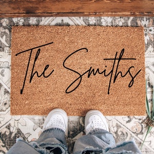 May include: A brown coir doormat with the text "The Smiths" in black cursive lettering.
