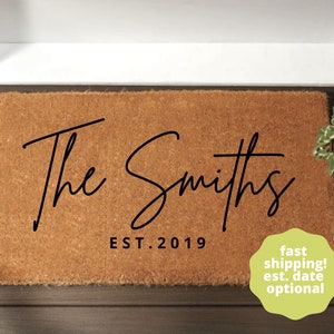 May include: A brown coir doormat with the text "The Smiths EST. 2019" in black script font.
