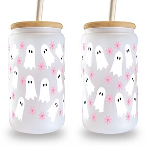 Two frosted glass can cups with white ghost and pink flower patterns, bamboo lids and straws on white.