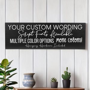 May include: Black wooden sign with white text that reads "YOUR CUSTOM WORDING Script Fonts Available MULTIPLE COLOR OPTIONS More colors! Hanging Hardware Included".