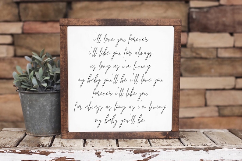 Brown framed sign with an affectionate handwritten style message, beside a succulent on a rustic shelf.