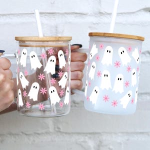 Clear and frosted handled glass cups with white ghosts and pink flowers, shown side by side.