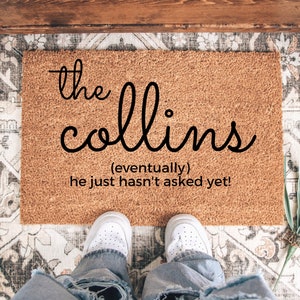 May include: A brown coir doormat with the text "the collins (eventually) he just hasn't asked yet!" in black lettering.
