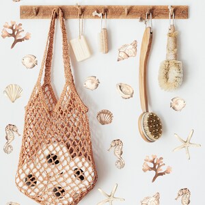 May include: A white wall with a wooden rack with a brown crocheted bag hanging from it. The wall is decorated with brown and beige sea-themed stickers, including starfish, seashells, seahorses, and seaweed.