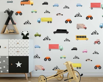 Peut inclure: Un mur blanc avec une variété d'autocollants de véhicules colorés, y compris des voitures, des camions et des bus. Les autocollants sont disposés de manière aléatoire et sont entourés d'autocollants en forme de galets noirs.