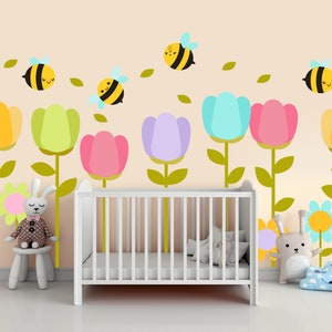May include: A white crib with a yellow, green, pink, and blue floral wall decal. The decal features bees and leaves.