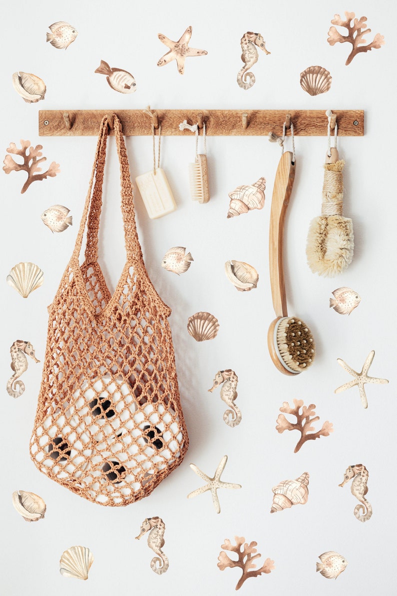 May include: A white wall with a wooden rack with a brown crocheted bag hanging from it. The wall is decorated with brown and beige sea-themed stickers, including starfish, seashells, seahorses, and seaweed.