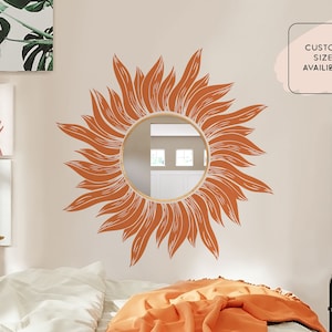 May include: A large orange sunflower decal with a round mirror in the center. The decal is on a white wall in a bedroom setting. The text "CUSTOM SIZE AVAILABLE" is in a white box on the wall.
