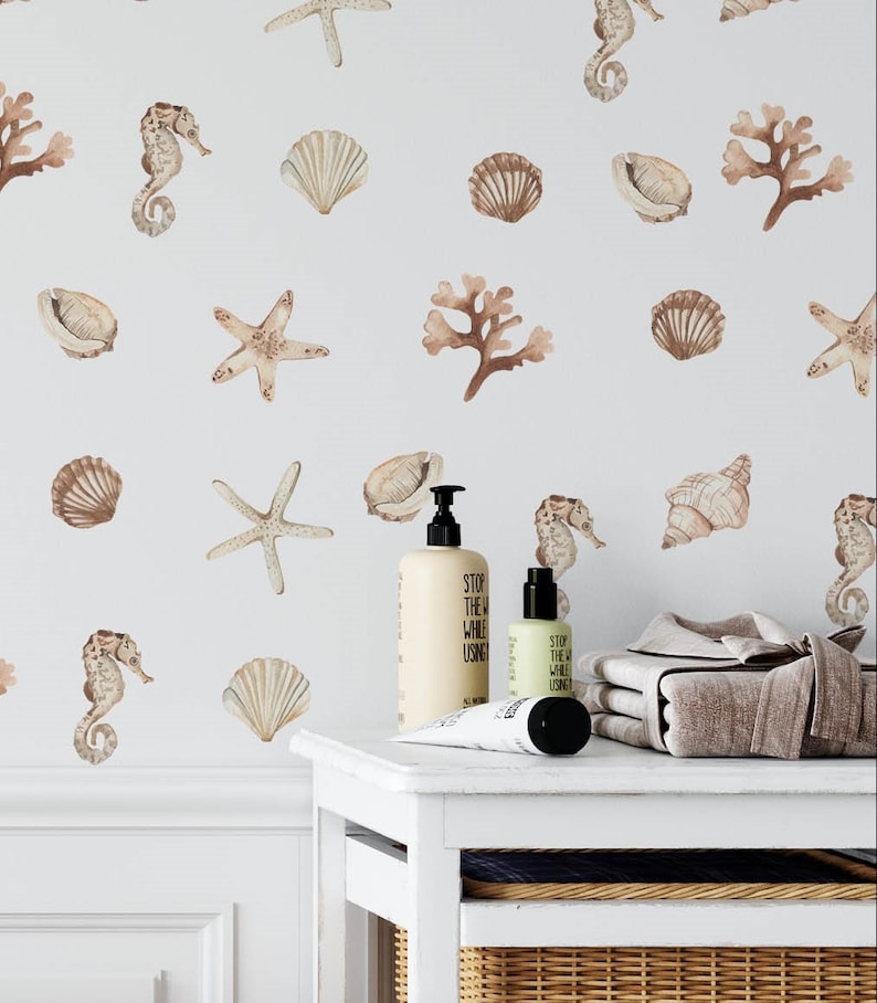 May include: A white bathroom with a white vanity and a wicker basket. The wall is decorated with brown and beige seahorse, starfish, and seashell decals. The vanity has two bottles of lotion and a tube of hand cream. The text on the bottles reads "Stop the world while using".