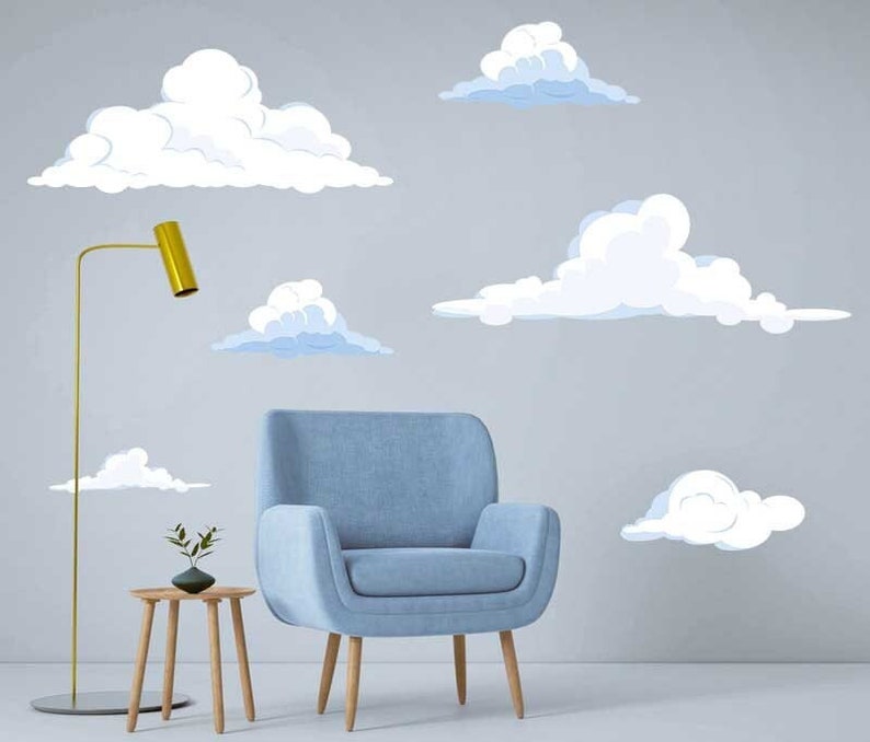 K&ouml;nnte beinhalten: Ein hellblauer Sessel steht vor einer Wand mit wei&szlig;en und hellblauen Wolken-Wandaufklebern. Die Wolken sind in verschiedenen Gr&ouml;&szlig;en und Formen.