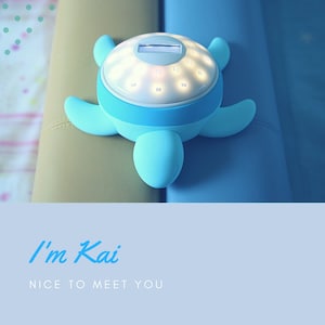 Può includere: Un timer a forma di tartaruga in plastica blu con un quadrante bianco e un display digitale. Il timer ha una luce che illumina i numeri. Il timer è su una superficie blu e beige. Il testo "I'm Kai" e "Nice to meet you" è scritto sotto il timer.