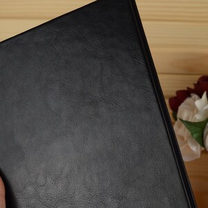 May include: A black leather-bound journal with a textured cover.