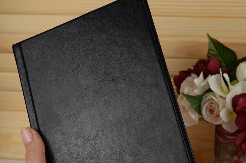 May include: A black leather-bound journal with a textured cover.