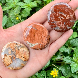May include: Three smooth, round, polished stones with a red, brown, and white marbled pattern. The stones are about 2 inches in diameter.