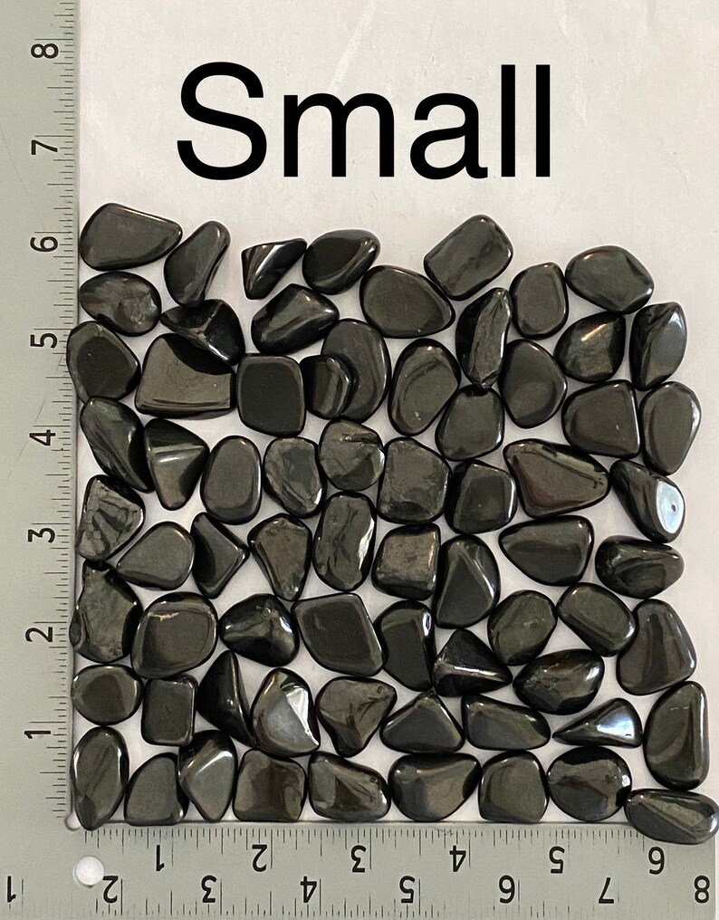May include: A collection of small, polished, black stones. The stones are smooth and rounded, with a glossy finish. The word "Small" is printed in large black letters above the stones. The stones are measured using inches.