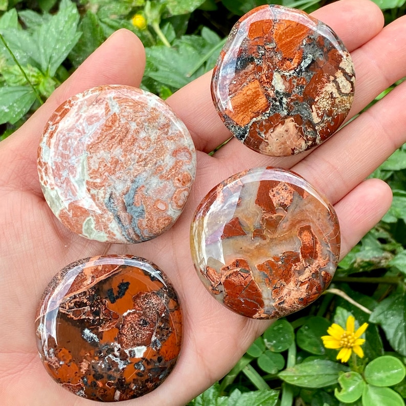 May include: Four smooth, round, polished stones with a red, brown, and white marbled pattern. The stones are about the size of a silver dollar.