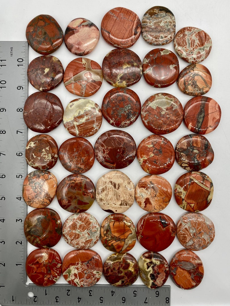 May include: A collection of 25 smooth, round, polished red, brown, and white jasper stones. The stones are approximately 1 inch in diameter and have a variety of patterns and textures.