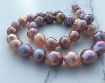 May include: A strand of baroque pearls in shades of pink, lavender, and white. The pearls are iridescent and have a natural, irregular shape.