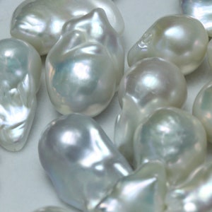 May include: A collection of white baroque pearls with an iridescent sheen. The pearls are various shapes and sizes, and some have a slightly irregular shape.