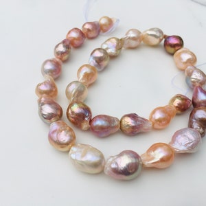 Puede incluir: Una hebra de perlas barrocas en tonos rosa, melocotón y blanco. Las perlas están enhebradas en un hilo blanco y están listas para ser utilizadas en la elaboración de joyas.