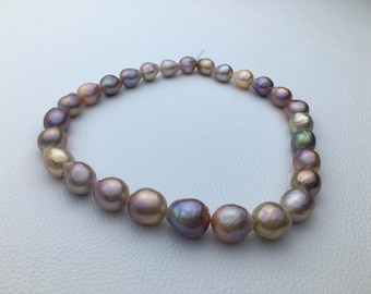 May include: A strand of iridescent pearls in shades of pink, lavender, and gold. The pearls are strung on a thin thread and are arranged in a circular shape.