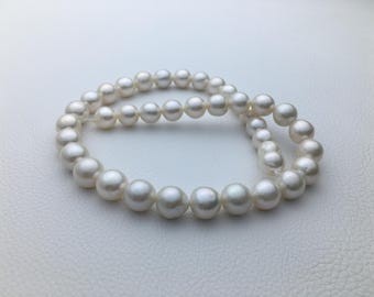 May include: A strand of white pearls, arranged in a circle, on a white background.