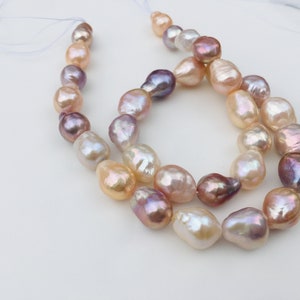 Puede incluir: Una hebra de perlas barrocas en tonos rosa, melocotón y lavanda. Las perlas están enhebradas en un cordón blanco y están dispuestas en un patrón suelto y fluido.