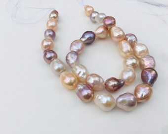 May include: A strand of baroque pearls in shades of pink, peach, and lavender. The pearls are strung on a white cord and are arranged in a loose, flowing pattern.