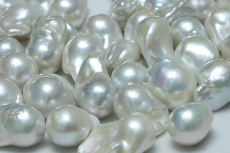 May include: A collection of white baroque pearls with an iridescent sheen. The pearls are various sizes and shapes, with some being more round and others more irregular.