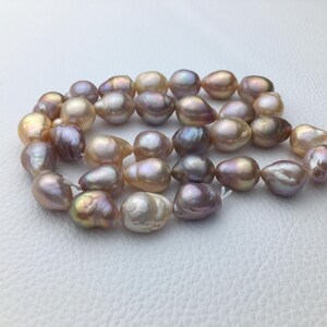 May include: A strand of baroque pearls in shades of pink, lavender, and white. The pearls are irregular in shape and have a lustrous sheen.