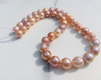 May include: A strand of iridescent pink and peach freshwater pearls. The pearls are strung on a white cord and are ready to be made into jewelry.
