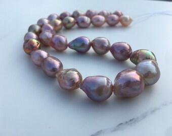 May include: A strand of iridescent, baroque-shaped pearls in shades of pink, lavender, and peach. The pearls are strung together, creating a necklace or bracelet. The surface of the pearls reflects light, displaying a shimmering effect.