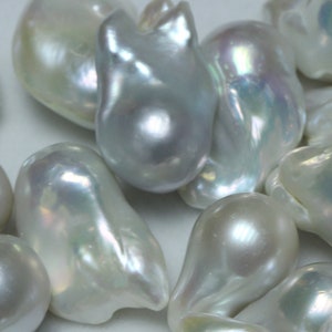 May include: A collection of white, pearlescent, baroque pearls of various shapes and sizes. The pearls have an iridescent sheen and are arranged on a white surface.