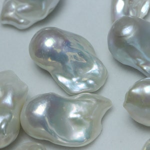 May include: A group of white baroque pearls with an iridescent sheen. The pearls are irregular in shape and have a smooth, glossy surface.
