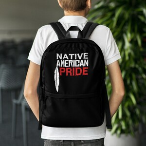 May include: Black backpack with a white feather design and the text "NATIVE AMERICAN PRIDE" in white letters with a red accent on the word "PRIDE".