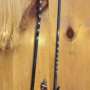 May include: Two black metal fireplace tools with leather loops. The tool on the left has a twisted handle and a hook at the end. The tool on the right has a straight handle and a hook at the end.