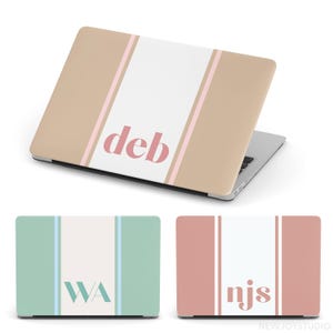 Könnte beinhalten: Laptop-Hülle mit beigem Hintergrund, einem weißen Mittelstreifen und rosa Akzentstreifen. Der Name "deb" ist in Rosa in einer Serifenschrift gedruckt. Zwei weitere Laptop-Hüllen sind abgebildet, eine in Mintgrün mit "WA" und eine weitere in Koralle mit "njs".