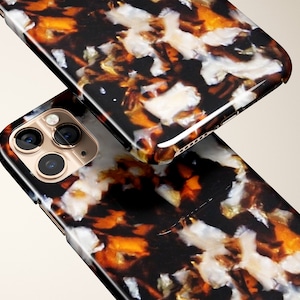 Op de afbeelding: Twee smartphonehoesjes met een schildpadpatroon. De hoesjes hebben een mix van zwarte, bruine, witte en gouden kleuren. De cameralenzen zijn zichtbaar op de onderste hoes. De hoesjes zijn waarschijnlijk ontworpen om de telefoon te beschermen.