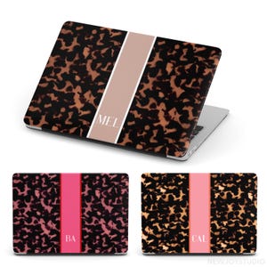May include: Laptop case with a tortoiseshell pattern and a vertical stripe. The stripe is a light tan color with the letters "MEL" in white. Two additional cases are shown with pink and coral stripes and initials.